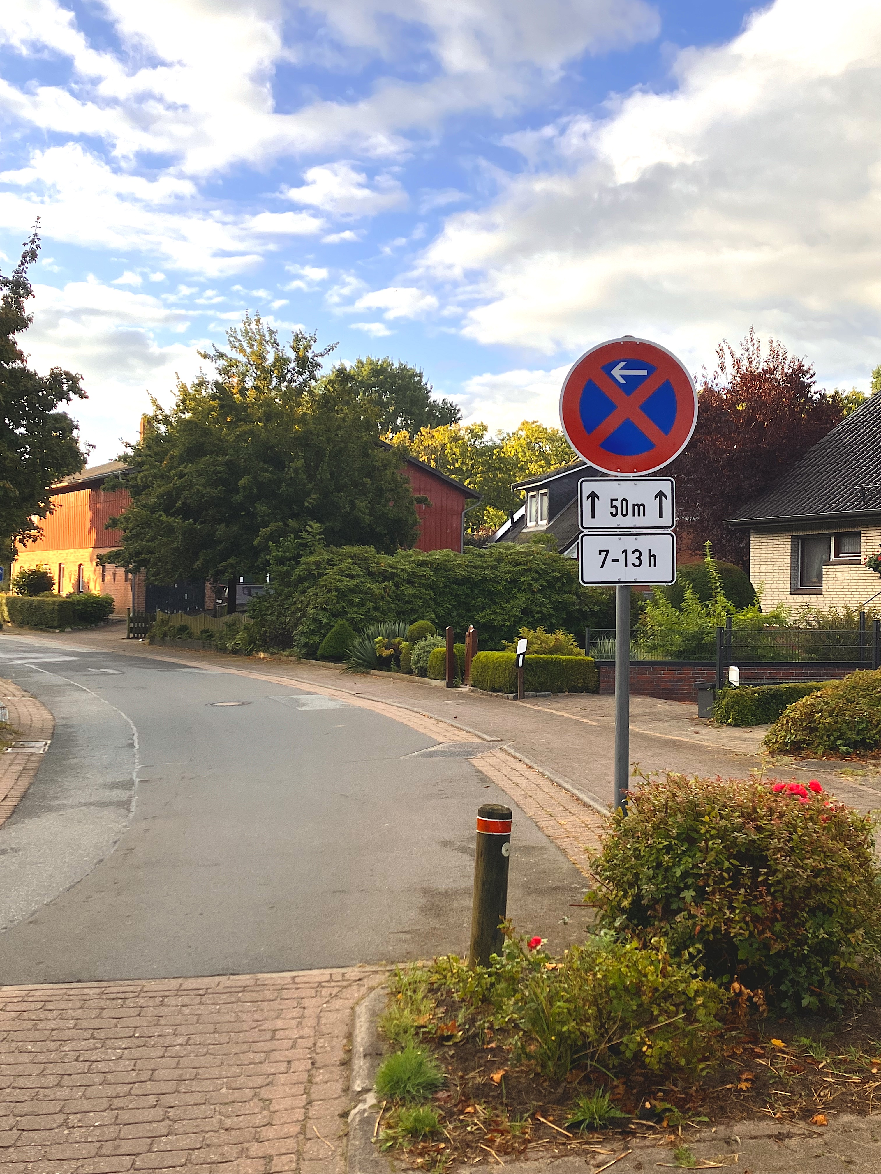 Das Bild zeigt den Bereich der Unterstraße, gegenüber der Grundschule in Oelixdorf. Darauf ein absolutes Halteverbotsschild mit der Kennzeichnung: 7-13 Uhr und geltend für den Bereich direkt gegenüber den Parkplätzen an der Grundschule.