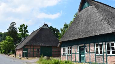 Alte Kate in Oelixdorf, im Hintergrund: Scheune des Landgasthofes Unter den Linden